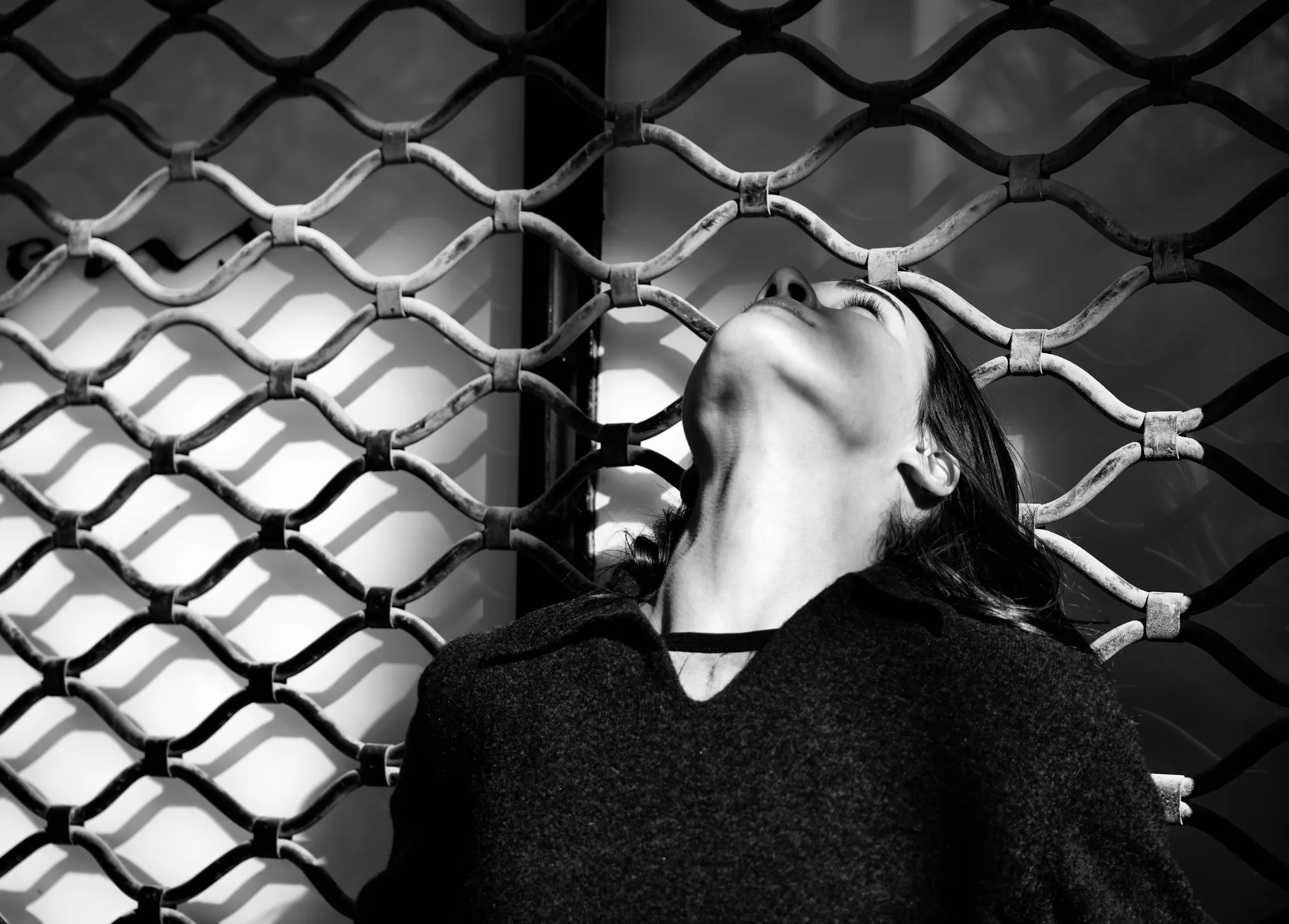 Book photo : portrait en noir et blanc, visage levé devant une grille, jeux de lumière